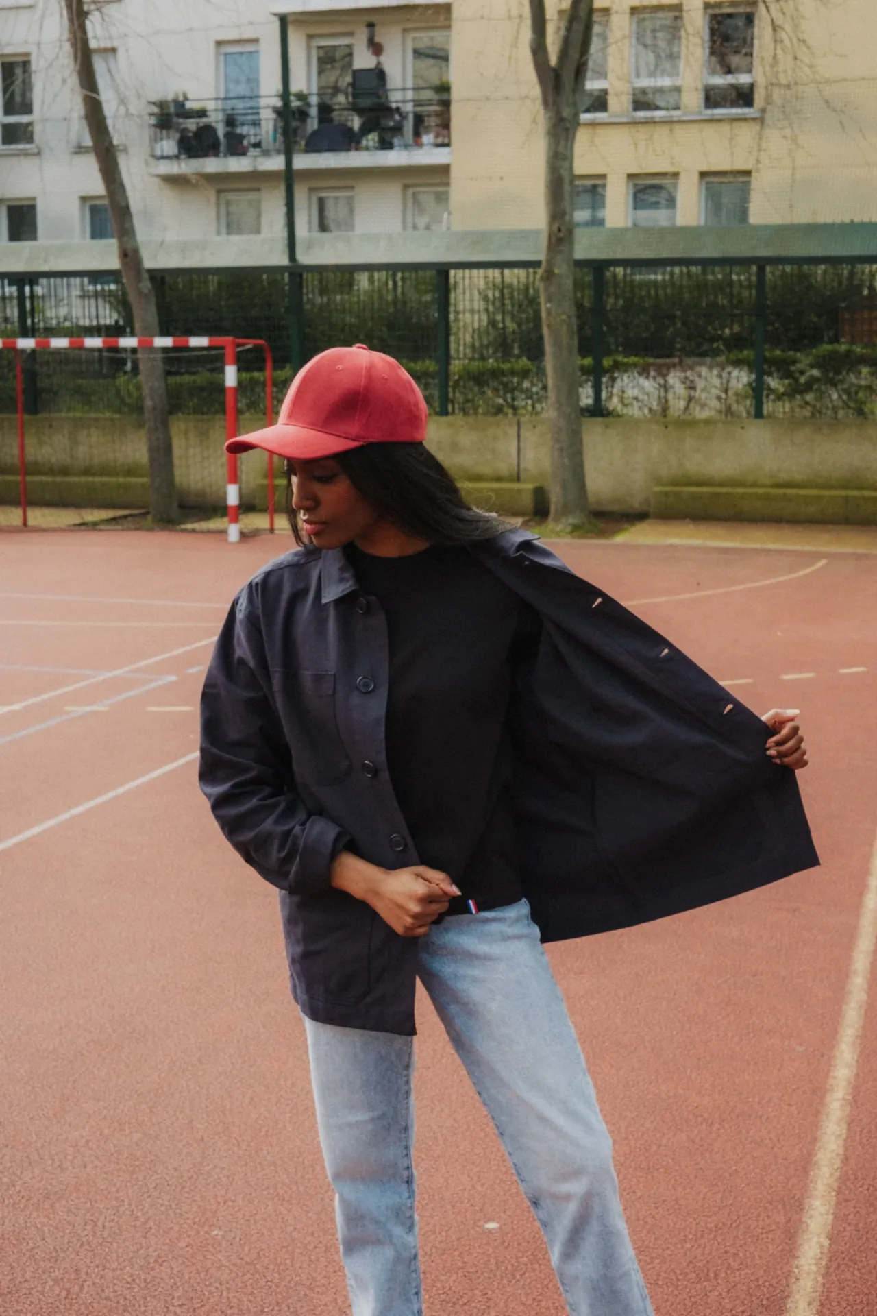 Une jeune femme modèle met en avant sa surchemise en toile sur un terrain de basketball.