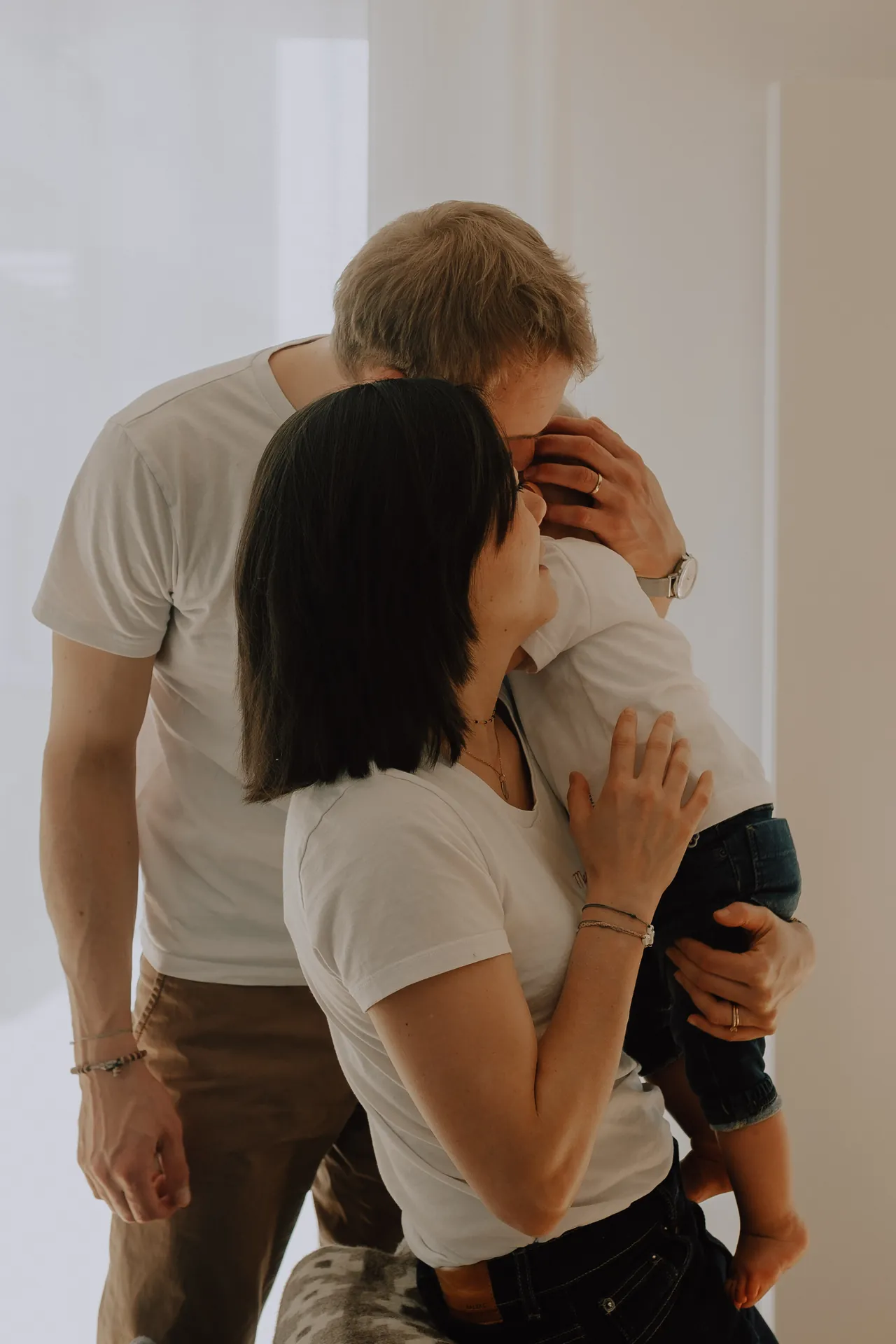 Une famille composée d'un homme, d'un femme et d'un enfant se prennent dans les bras lorsd'une séance photos de famille couverte par Jeremy Dan, photographe lifestyle.