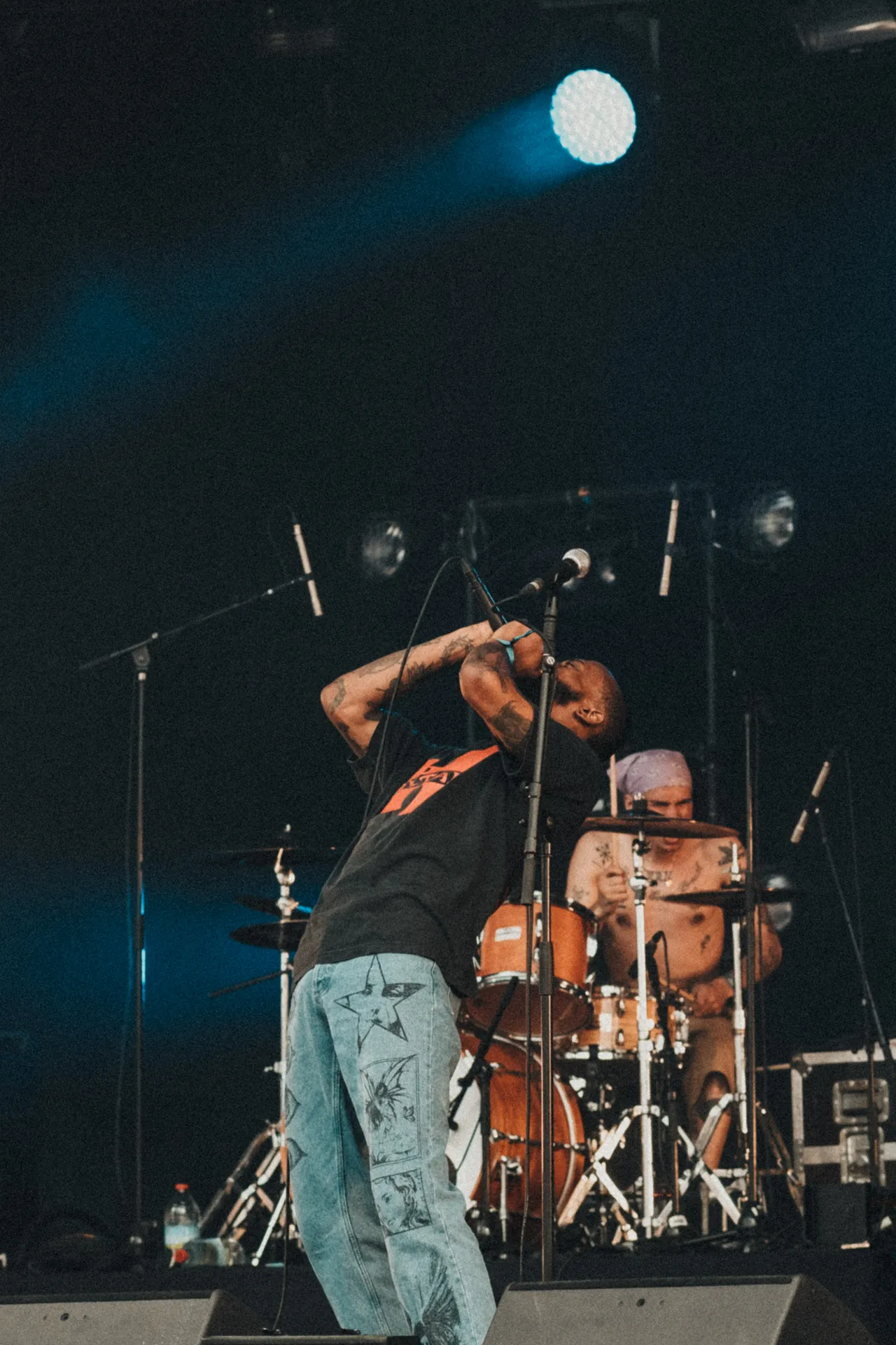 Le chanteur de Jesus Piece chante sur scène au Hellfest avec son groupe. Le batteur est à l'arrière.