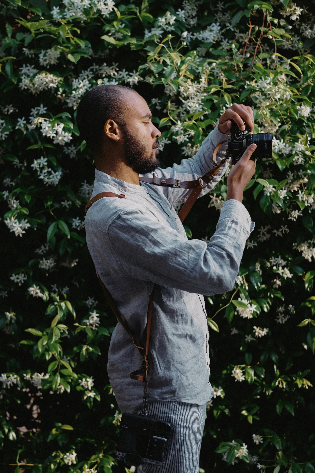 Jeremy Dan, photographe de mariage, d'entreprise, couple, famille et événementiel basé à Sceaux, prend une photo devant une haie.