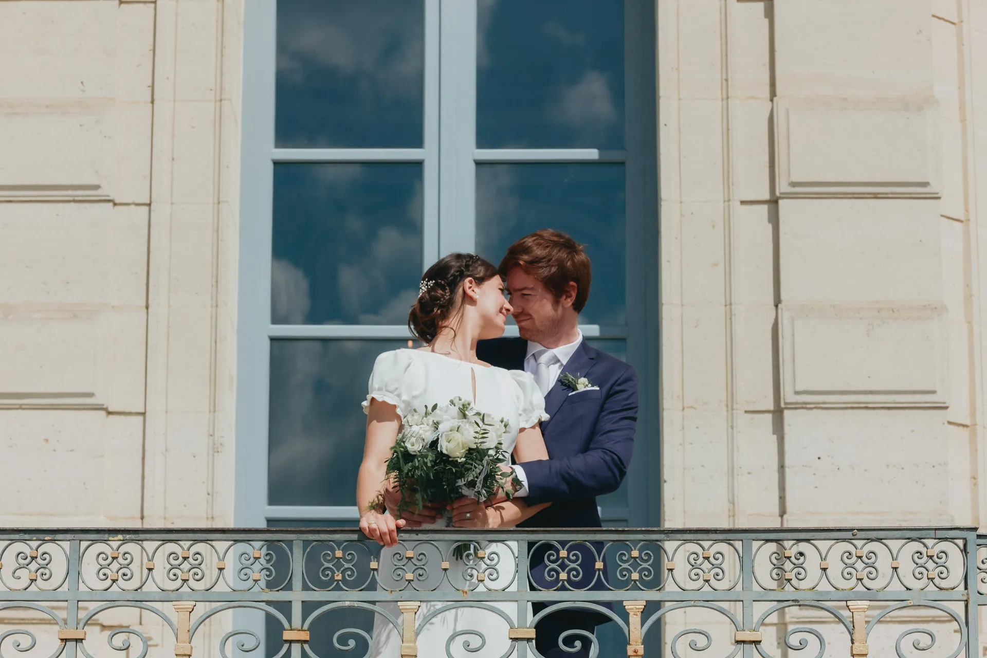 Le marié et la mariée se regardent tendrement devant l'entrée du château de Sceaux.